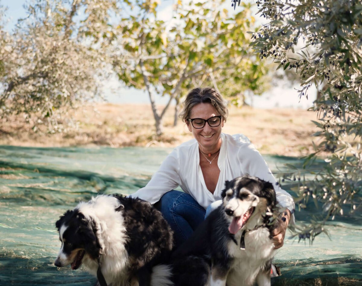 our founder with two dogs in the olive garden at podere l'agave San Vincenzo