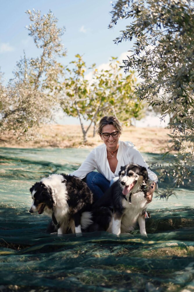 our founder with two dogs in the olive garden at podere l'agave San Vincenzo