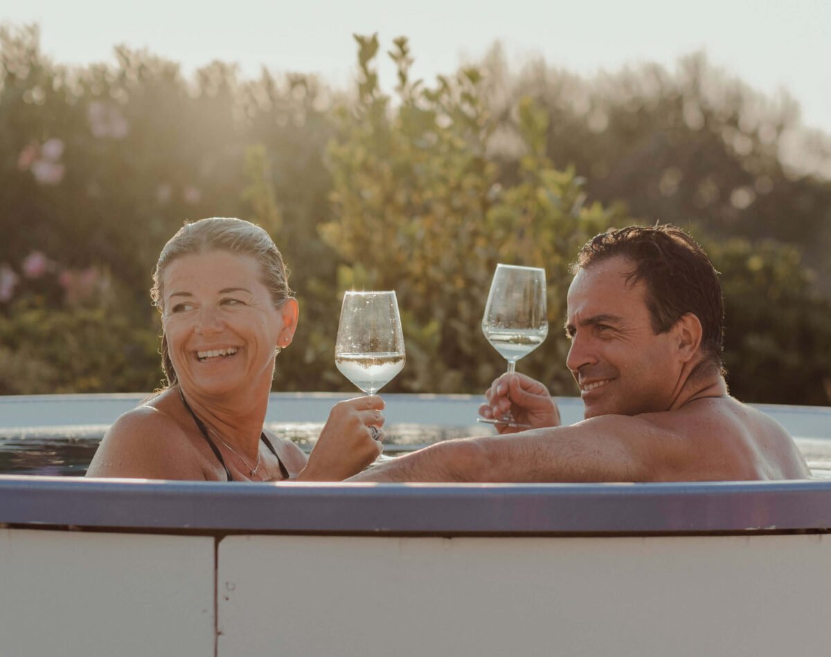 happy couple toasting in the hot tub at sunset