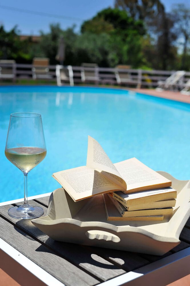 reading by the pool with a glass of wine